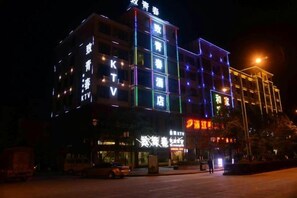 A multi-story hotel with illuminated signage and a well-lit facade. - Qujing Youth Network Hotel (Qujing)