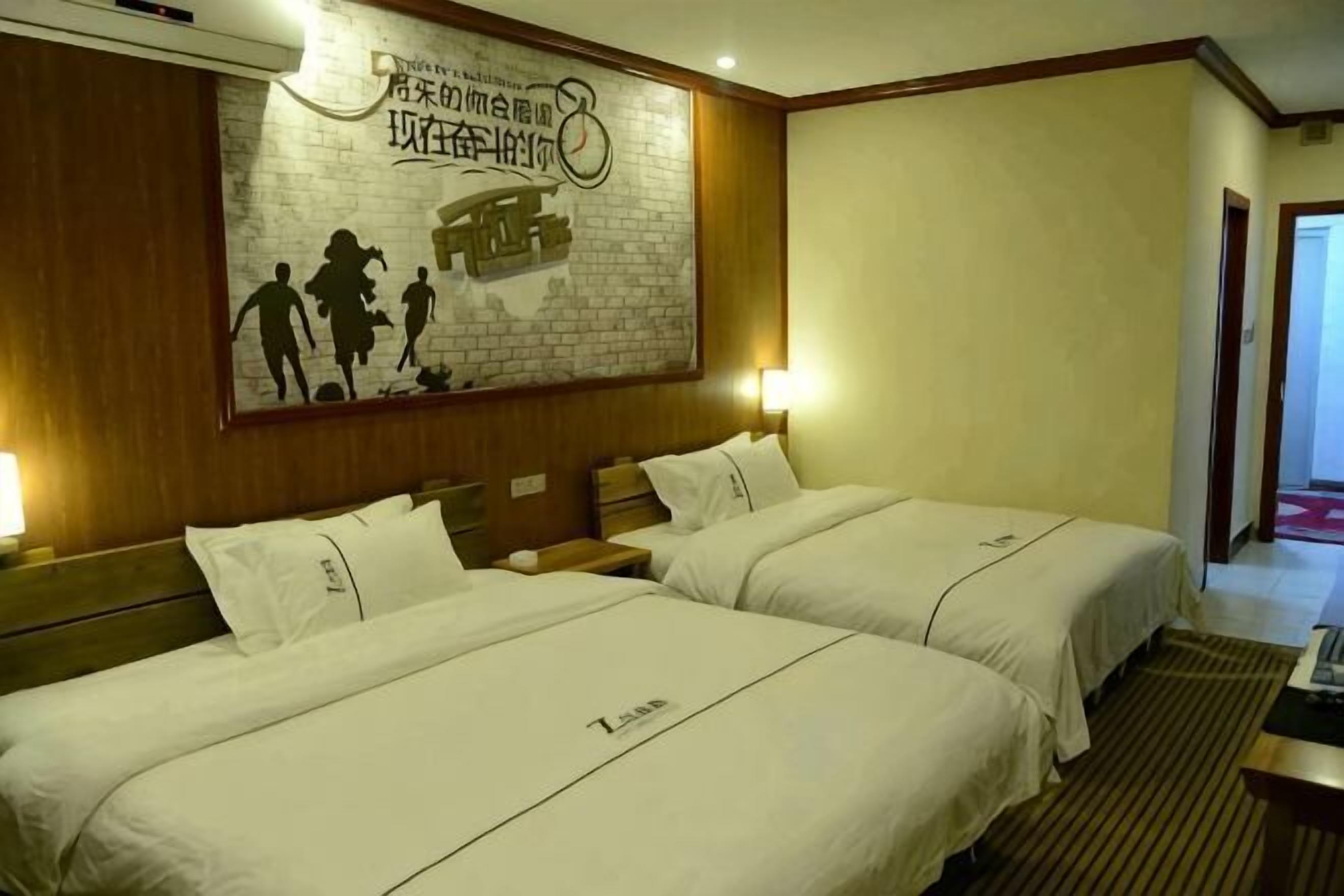 A hotel room with two beds, a brick-patterned wall, and a mural.