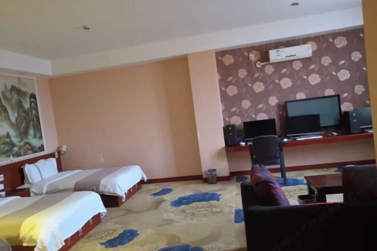 A hotel room with two beds, a desk with a computer, a television, and a carpeted floor.