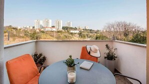 Un balcon avec une table, des chaises, un pot de fleurs et un livre.