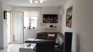 Un salon moderne avec un canapé en cuir, un fauteuil noir et un téléviseur à écran plat fixé au mur.