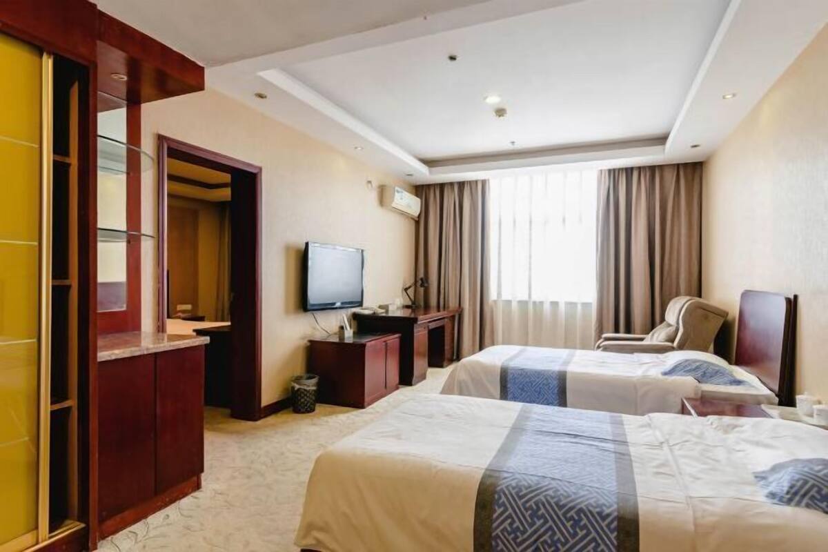 A hotel room with two beds, a TV, a desk, and a chair.