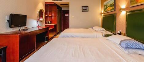 A hotel room with two beds, a desk with a television, and a mirror.