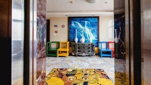 Quarto com carpete estampado, uma pintura grande e um armário com objetos em cima.