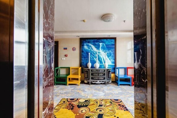 A room with a patterned carpet, a large painting, and a cabinet with items on top. - Wanshui Qianshan Hotel (Xiuwu)