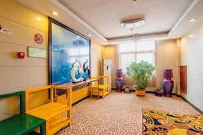 A lobby with a reception desk, seating area, large potted plant, and decorative vases. - Wanshui Qianshan Hotel (Xiuwu)