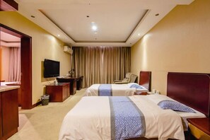 Habitación de hotel con dos camas, un escritorio, una silla, un televisor y una cortina.