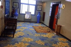 A hotel lobby with a patterned carpet, a reception desk, and a number sign. - Wanshui Qianshan Hotel (Xiuwu)