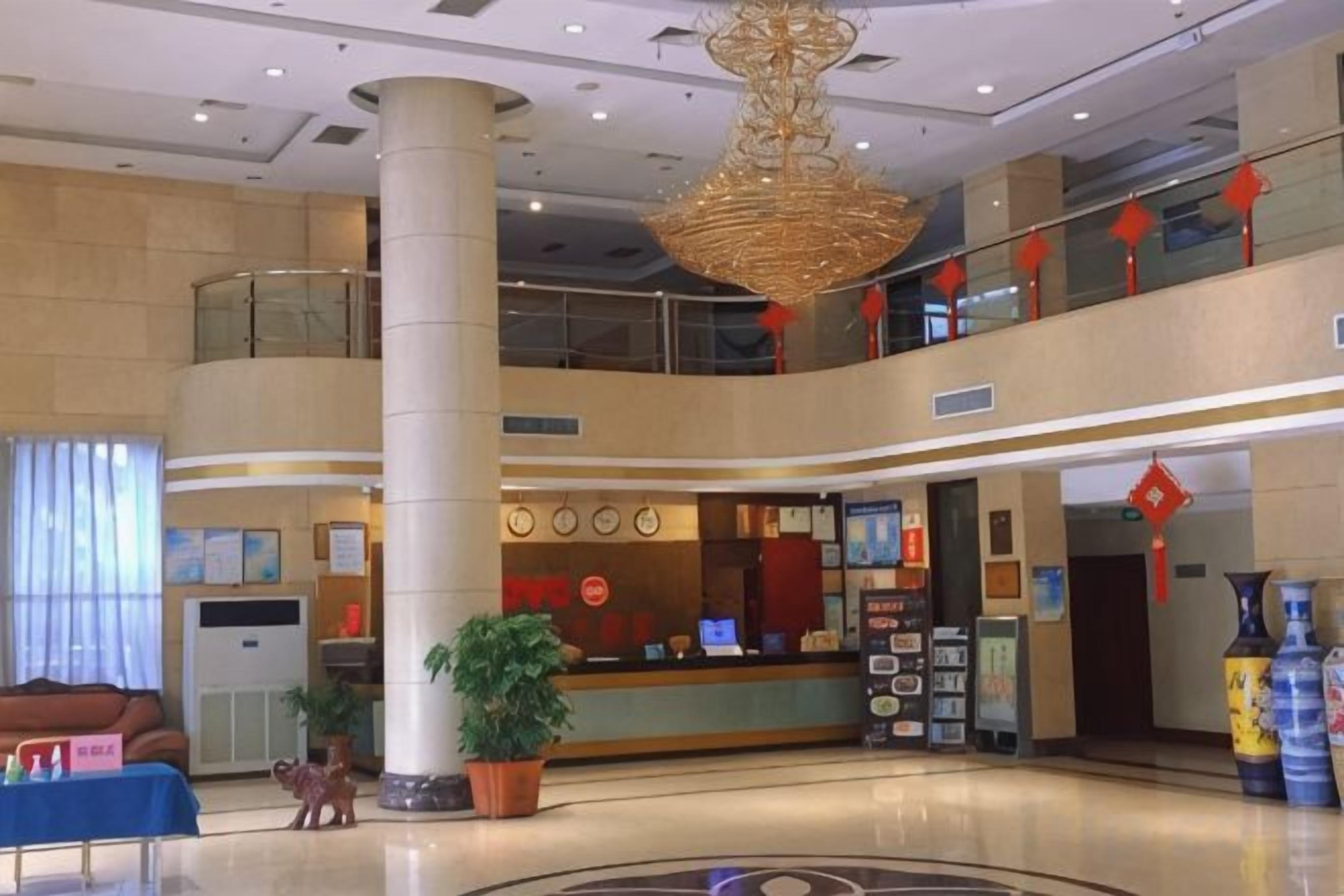 Eine Hotelhalle mit einer Rezeption, einer großen Säule und einem kreisförmigen Bodenmuster.