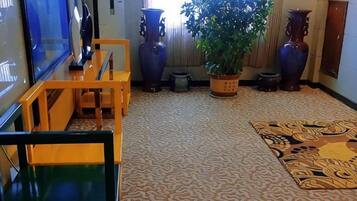 A room with patterned carpet, a wooden bench, a potted plant, and two vases.