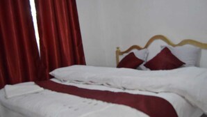 A neatly made bed with white bedding and red accents, a wooden headboard, and red curtains. - Stay.Plus Mwanzo Apartment Eldoret (Eldoret)