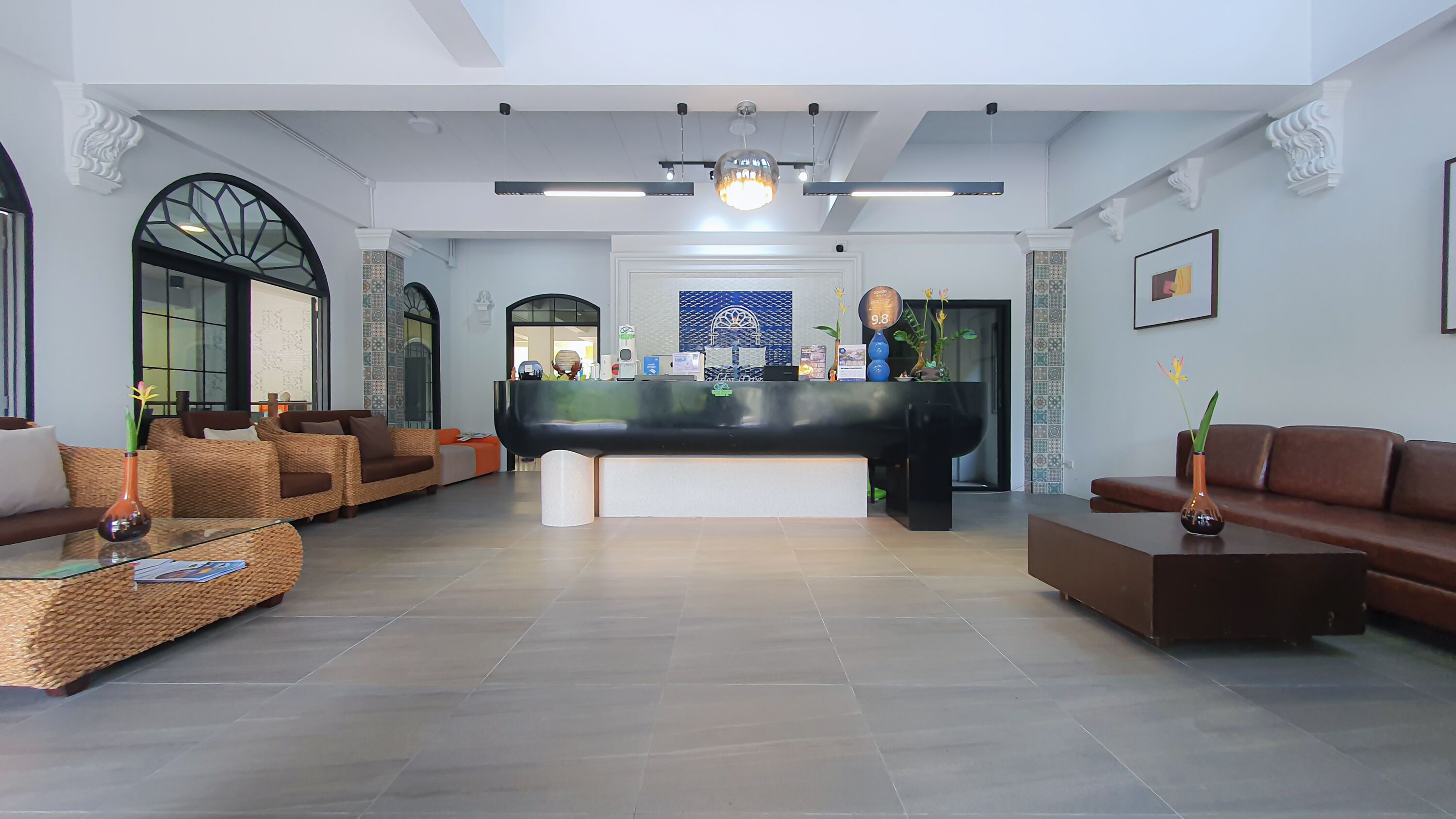 Un hall d’entrée spacieux avec un comptoir de réception, des coins salon confortables et un lustre moderne.