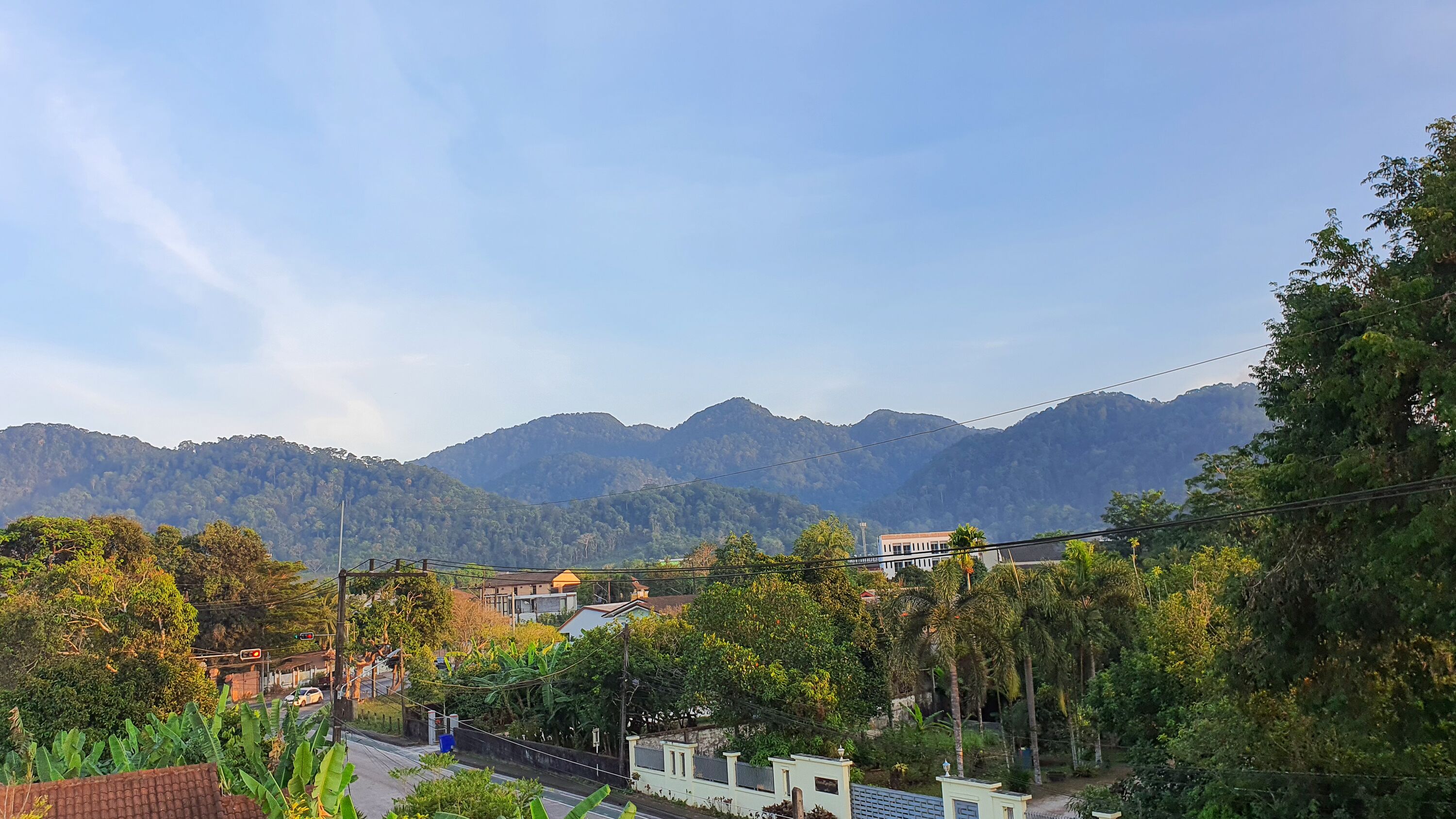 A residential area with houses, a road, and a mountain range in the background.