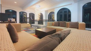 A spacious living area with a modern sofa set, a coffee table, and a decorative light fixture. - Daddy Dream Hotel and Residence (Ranong)