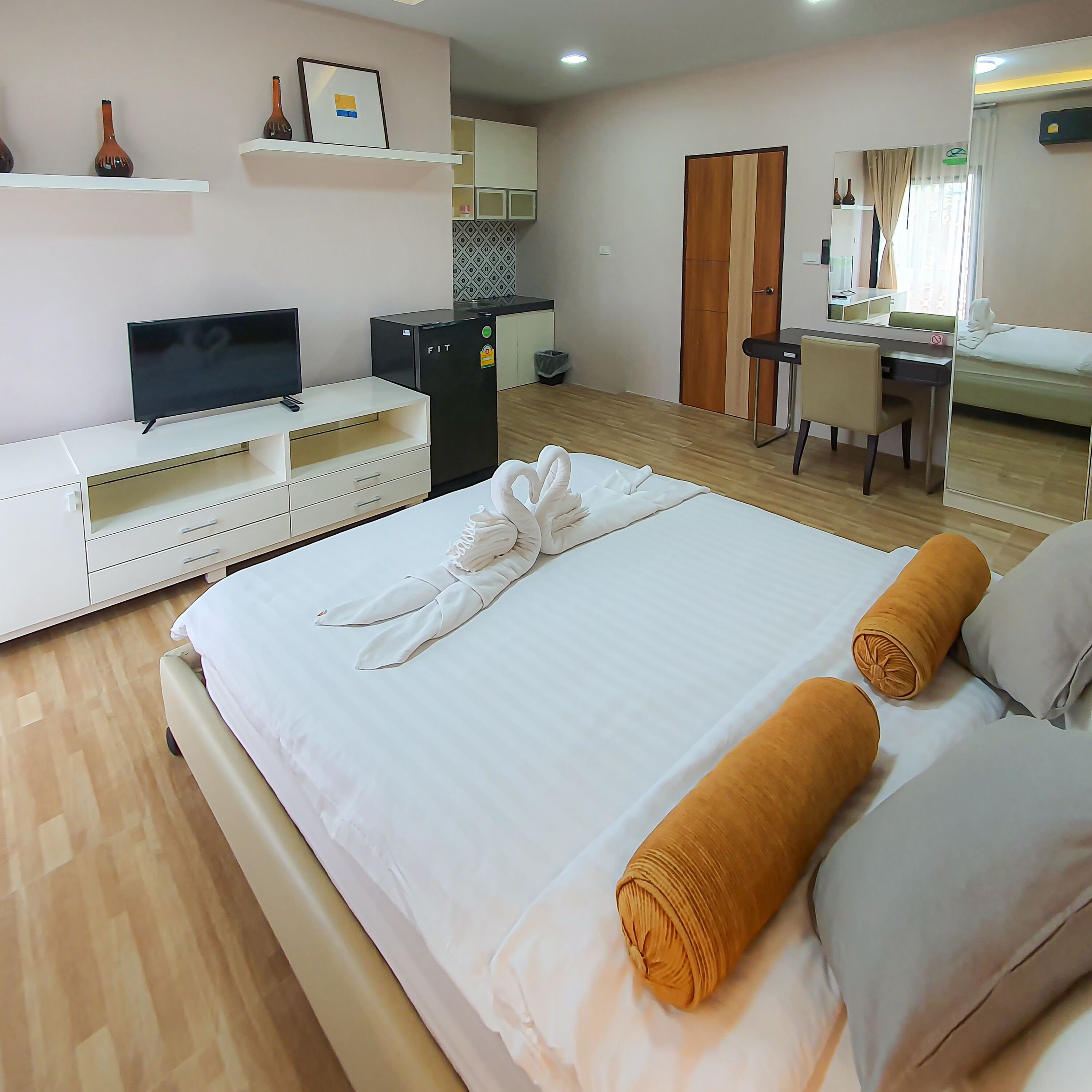 A hotel room with a bed, a TV, a desk, a chair, and a wardrobe.
