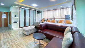 A modern hotel room with a large bed, a sofa, a small table, and a wardrobe. - Daddy Dream Hotel and Residence (Ranong)