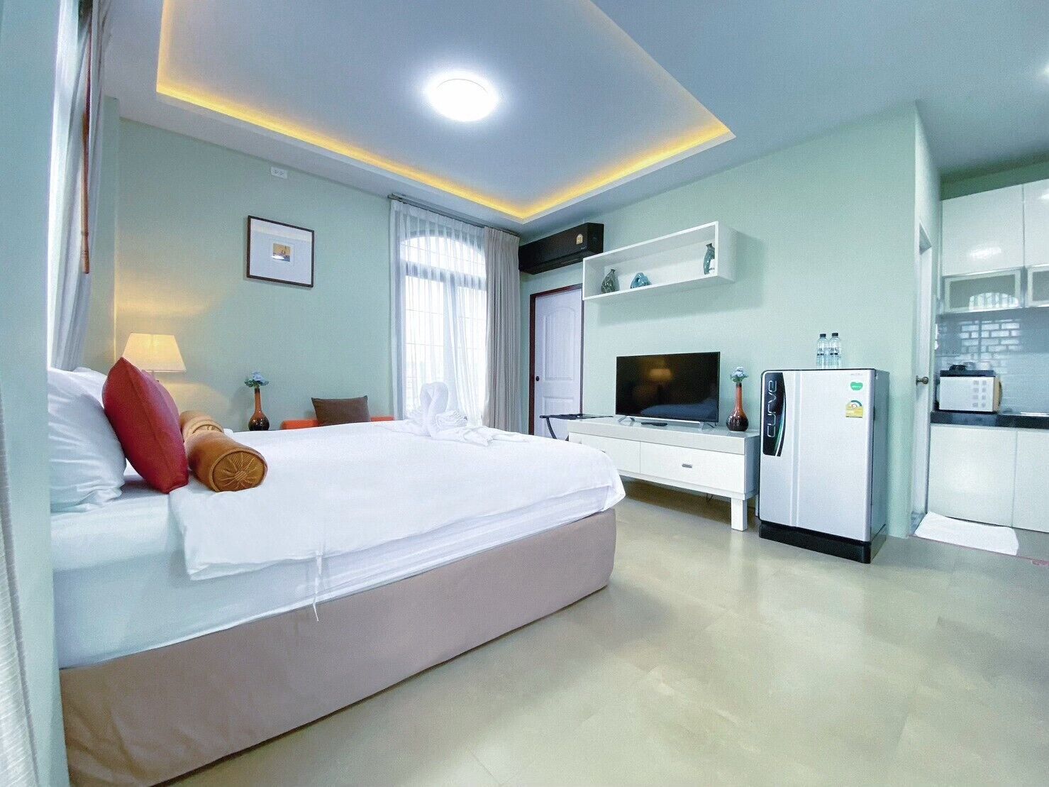 Habitació d'hotel amb llit, televisió, mini-nevera i cuineta.