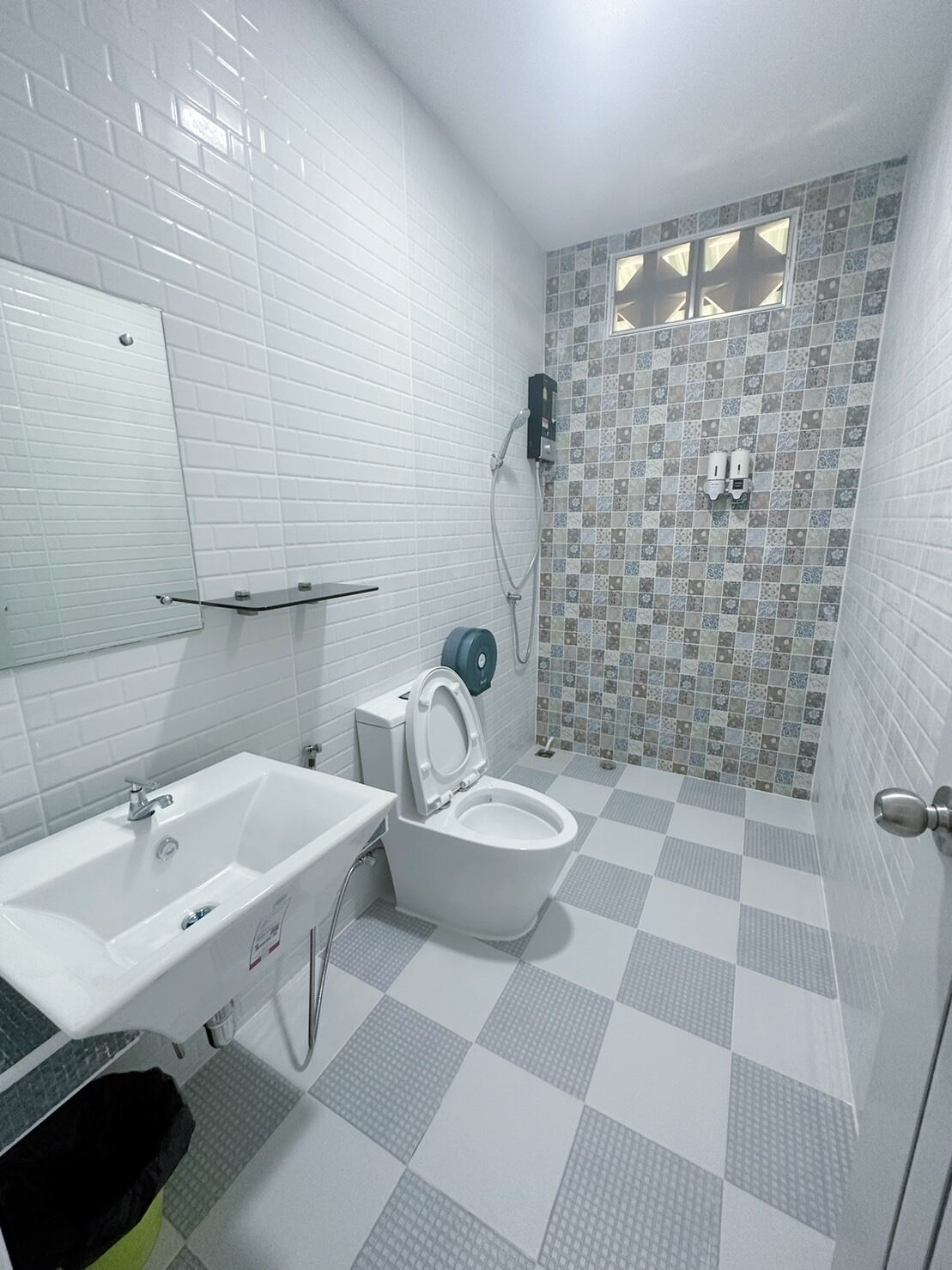 Un baño con lavamanos, inodoro y zona de ducha blanca.
