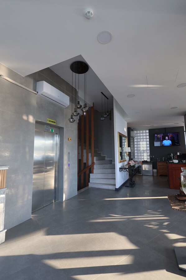 A modern interior with a central staircase, a flat-screen TV, and a visible elevator. - Tasliman Otel (Cinarcik)