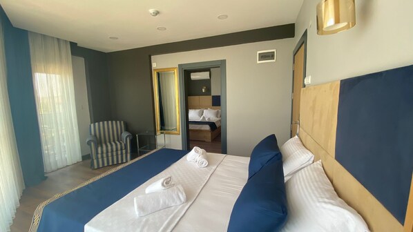 Habitación de hotel con una cama grande, una silla, un escritorio y un baño visible a través de una puerta abierta.