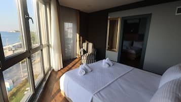 Habitación de hotel con una cama grande, una silla, un espejo y vistas al mar.