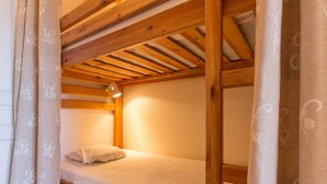 Un lit superposé avec une tête de lit, une table de chevet et une lampe.