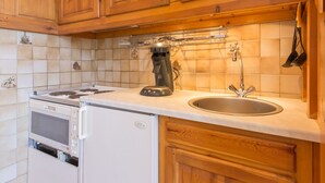 Une cuisine avec des meubles de rangement en bois, une cuisinière, un four à micro-ondes et un évier.