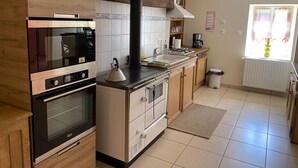 A modern kitchen with stainless steel appliances, wooden cabinets, a black exhaust hood, and a window with curtains. - Peaceful farmhouse with valley view and terrace (Mazirat)