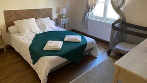 A neatly made bed with a green blanket, a bedside table with a lamp, and a window with curtains. - Peaceful farmhouse with valley view and terrace (Mazirat)