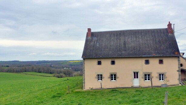 A two-story house with a sloped roof, a small porch, and a fenced yard. - Peaceful farmhouse with valley view and terrace (Mazirat)
