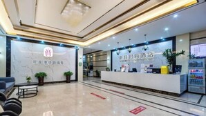 A hotel reception area with a marble floor, a reception desk, a seating area with chairs, and a vending machine. - Xinjia Fashion Hotel (Guangzhou Shigang East Village Store) (Guangzhou)