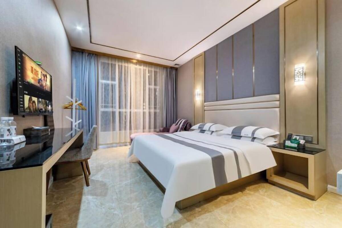 Een moderne hotelkamer met een bed, bureau en televisie.
