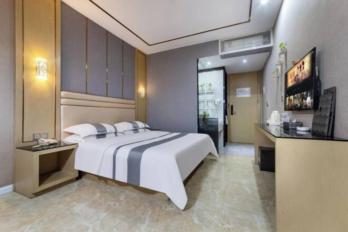 Een moderne hotelkamer met een bed, nachtkastje en een bureau met een flatscreen televisie.