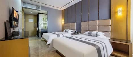 A hotel room with two beds, a TV, a wooden cabinet, and a wall-mounted light fixture.
