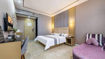 A modern hotel room with a bed, a desk, a chair, a TV, and a sofa.
