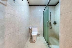 Een moderne badkamer met een toilet, een glazen douchecabine en een betegelde vloer.