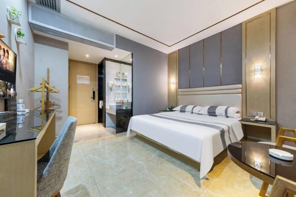 Habitación de hotel con una cama grande, un escritorio, una silla y un espejo.