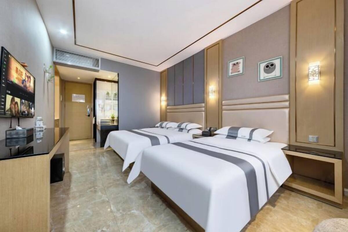 Een hotelkamer met twee bedden, een bureau en een televisie.