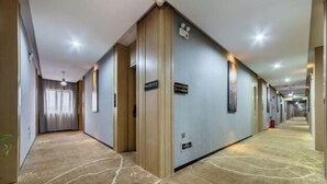 A hotel corridor with carpeted floors, wooden doors, and signs indicating room numbers. - Xinjia Fashion Hotel (Guangzhou Shigang East Village Store) (Guangzhou)