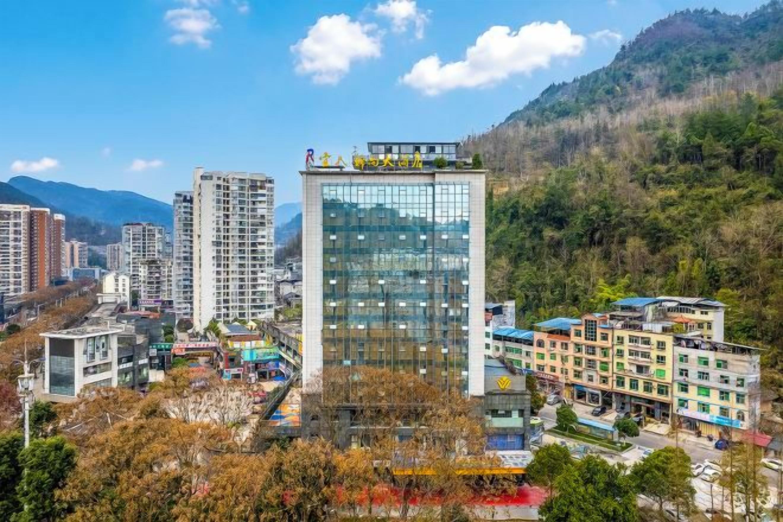 A modern hotel with multiple floors, surrounded by a mountainous landscape.