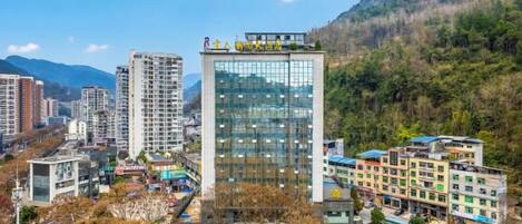 A modern hotel with multiple floors, surrounded by a mountainous landscape.