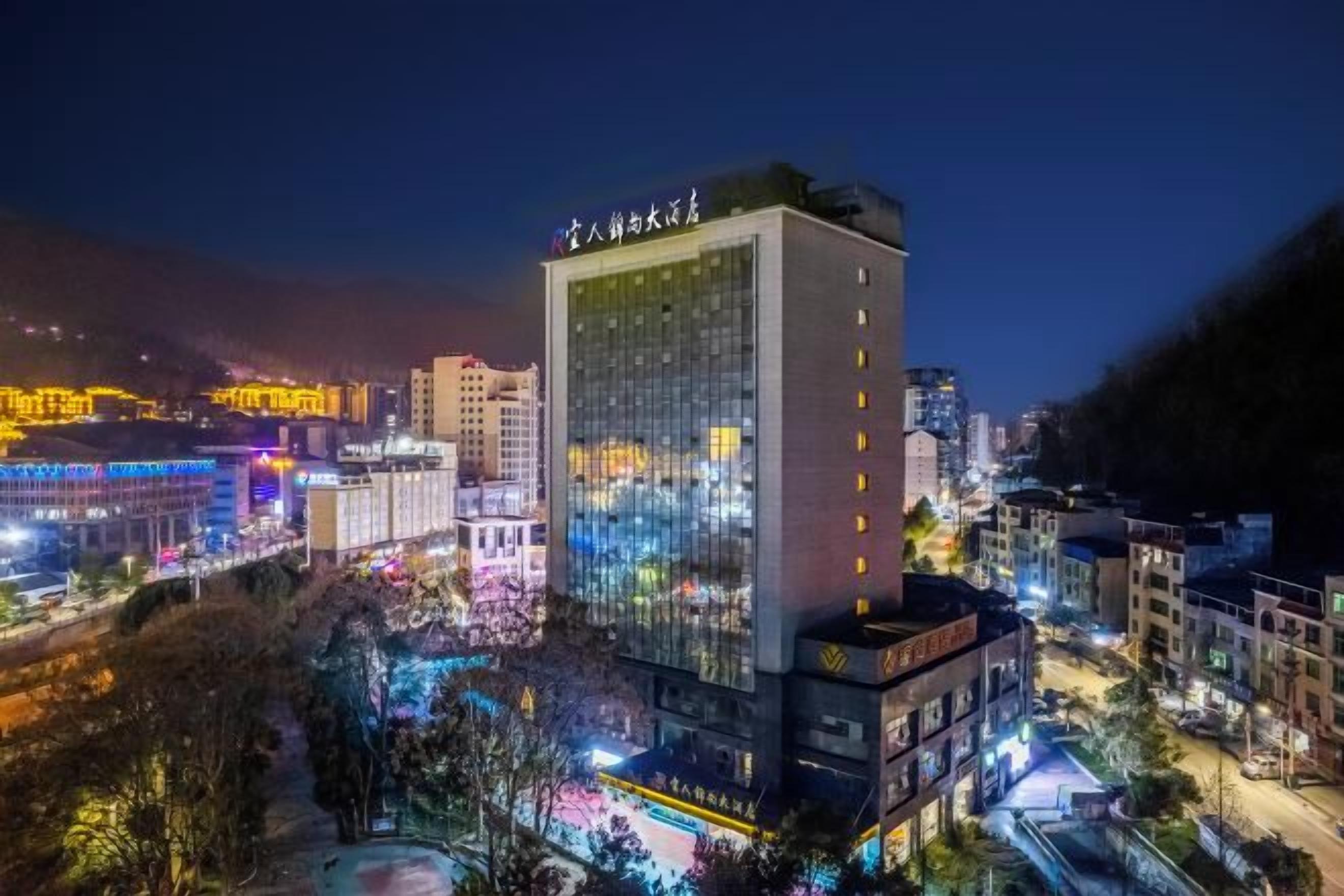 Un edificio de gran altura con varios pisos, rodeado por un paisaje urbano nocturno.