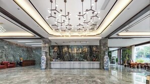 Een moderne lobby met een marmeren vloer, een receptiebalie en een unieke kroonluchter.