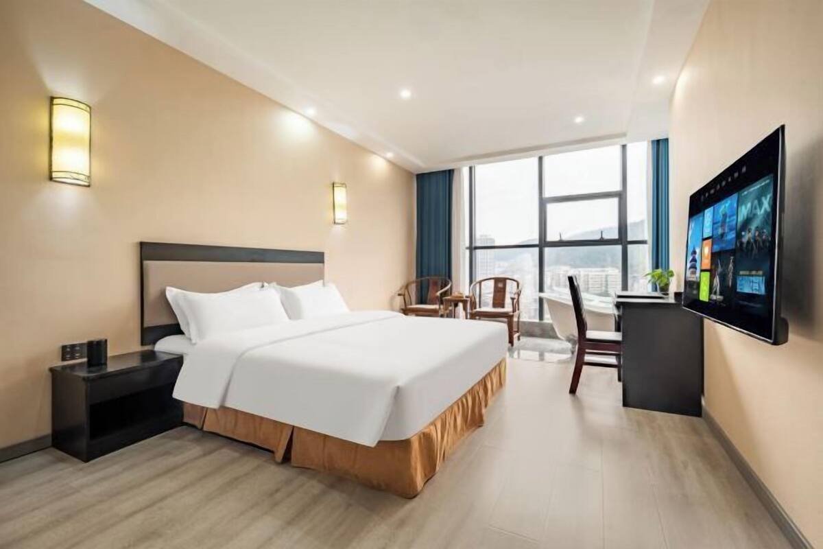 Ein Hotelzimmer mit Bett, Nachttisch, Fernseher und Schreibtisch mit Stuhl.