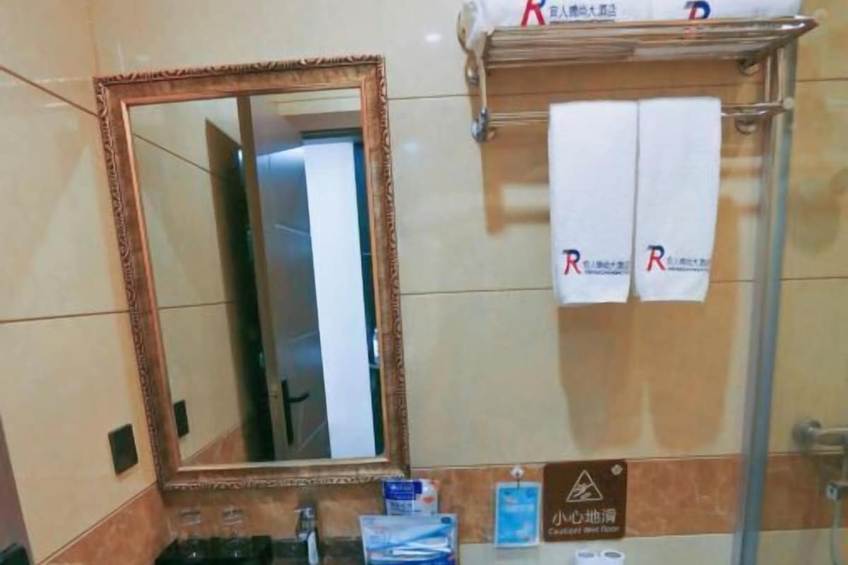 A bathroom with a marble countertop, a sink, a toilet, a glass shower enclosure, and a towel rack with towels.