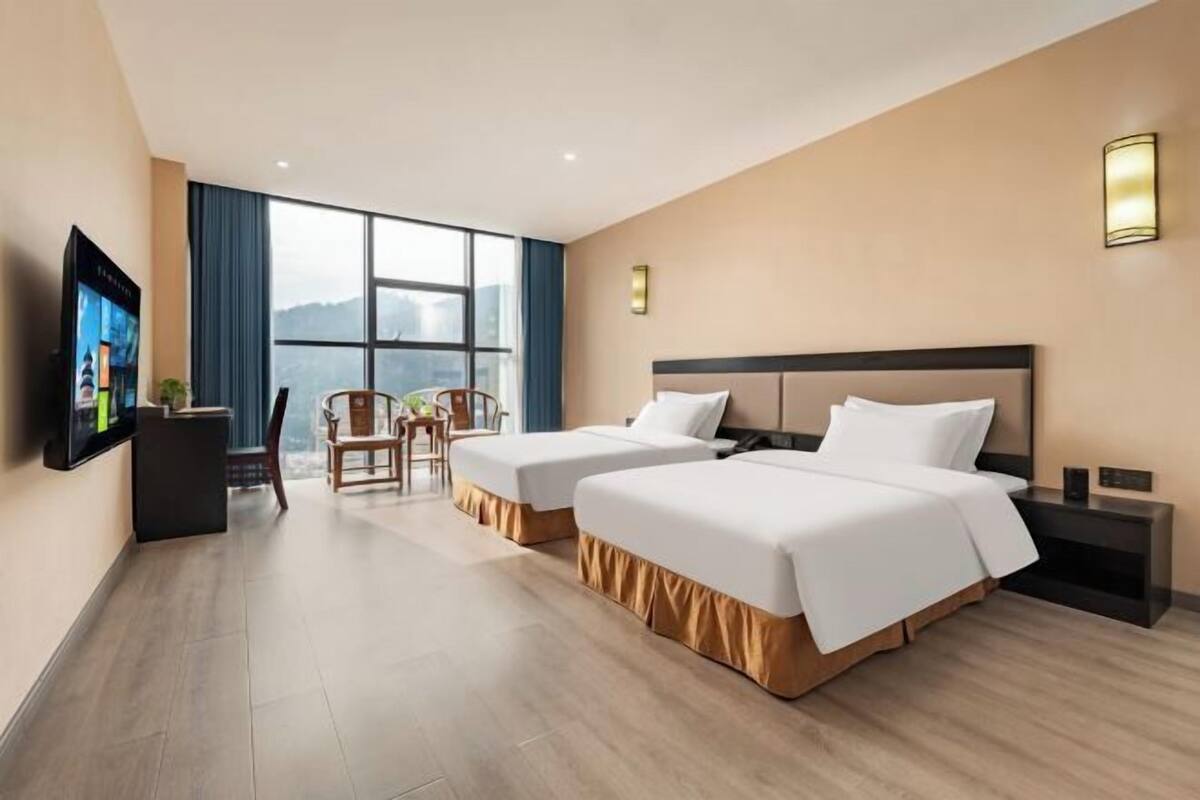 Ein Hotelzimmer mit zwei Betten, einem Fernseher, einem Schreibtisch und einem Sessel.