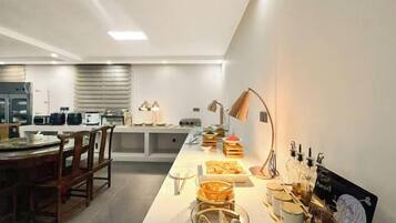 Een moderne keuken met een centraal eiland, voorzien van diverse apparaten en een eethoek met stoelen.