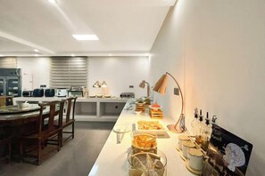 Una cocina moderna con una isla central, equipada con diversos electrodomésticos y un comedor con sillas.