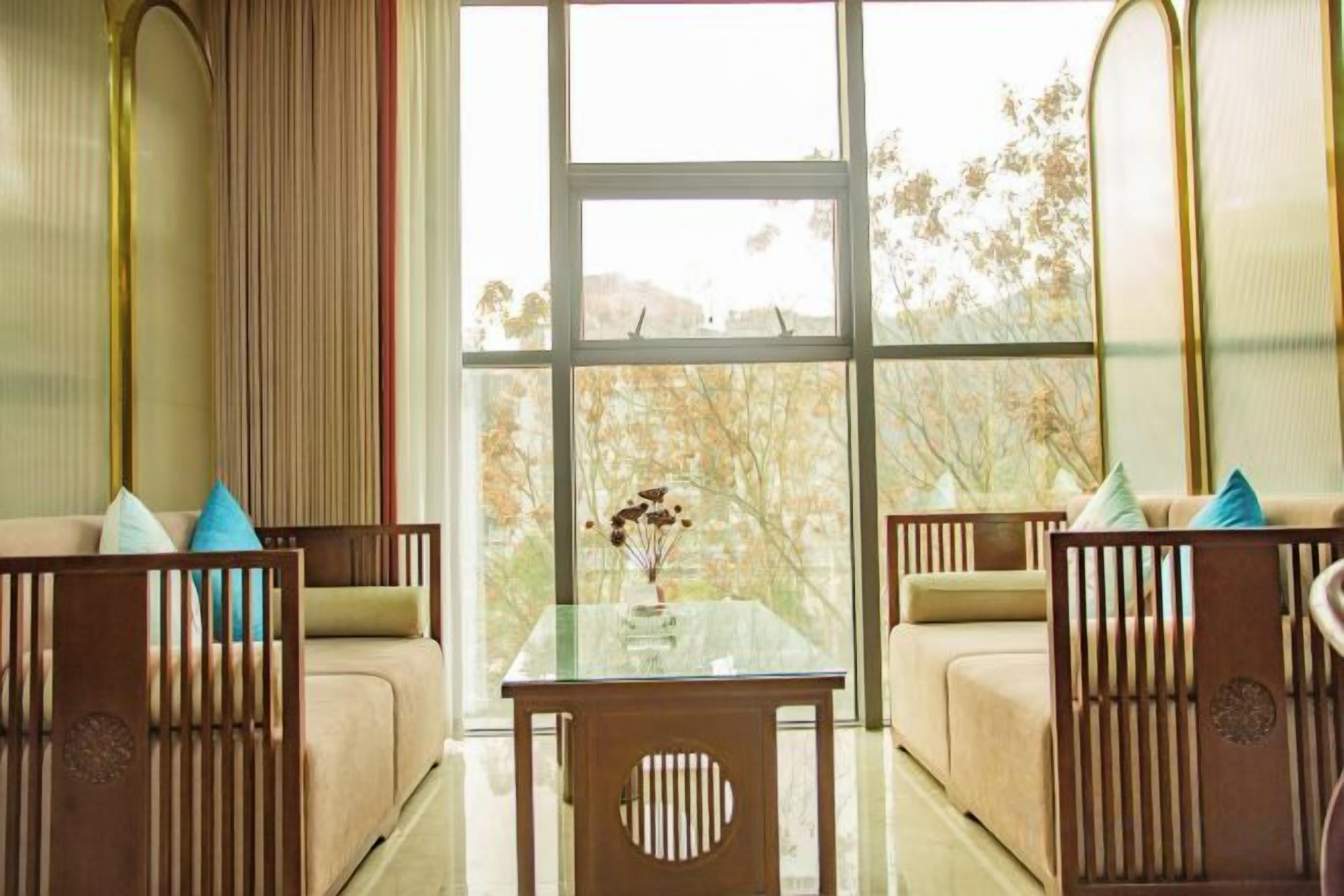 A room with a large window, a sofa, a table, and a chair.