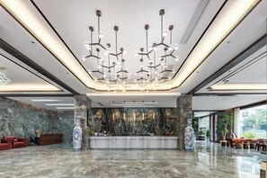 Een moderne lobby met een marmeren vloer, een receptiebalie en een bijzondere kroonluchter.